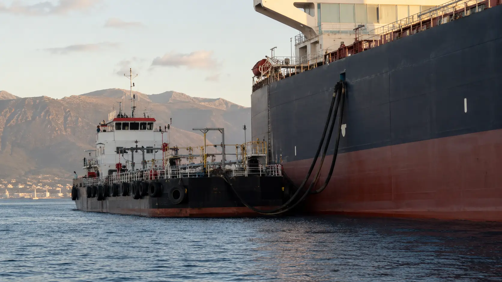 Bunker barge supplying marine fuel to a merchant vessel at anchor in the Bay of Algeciras