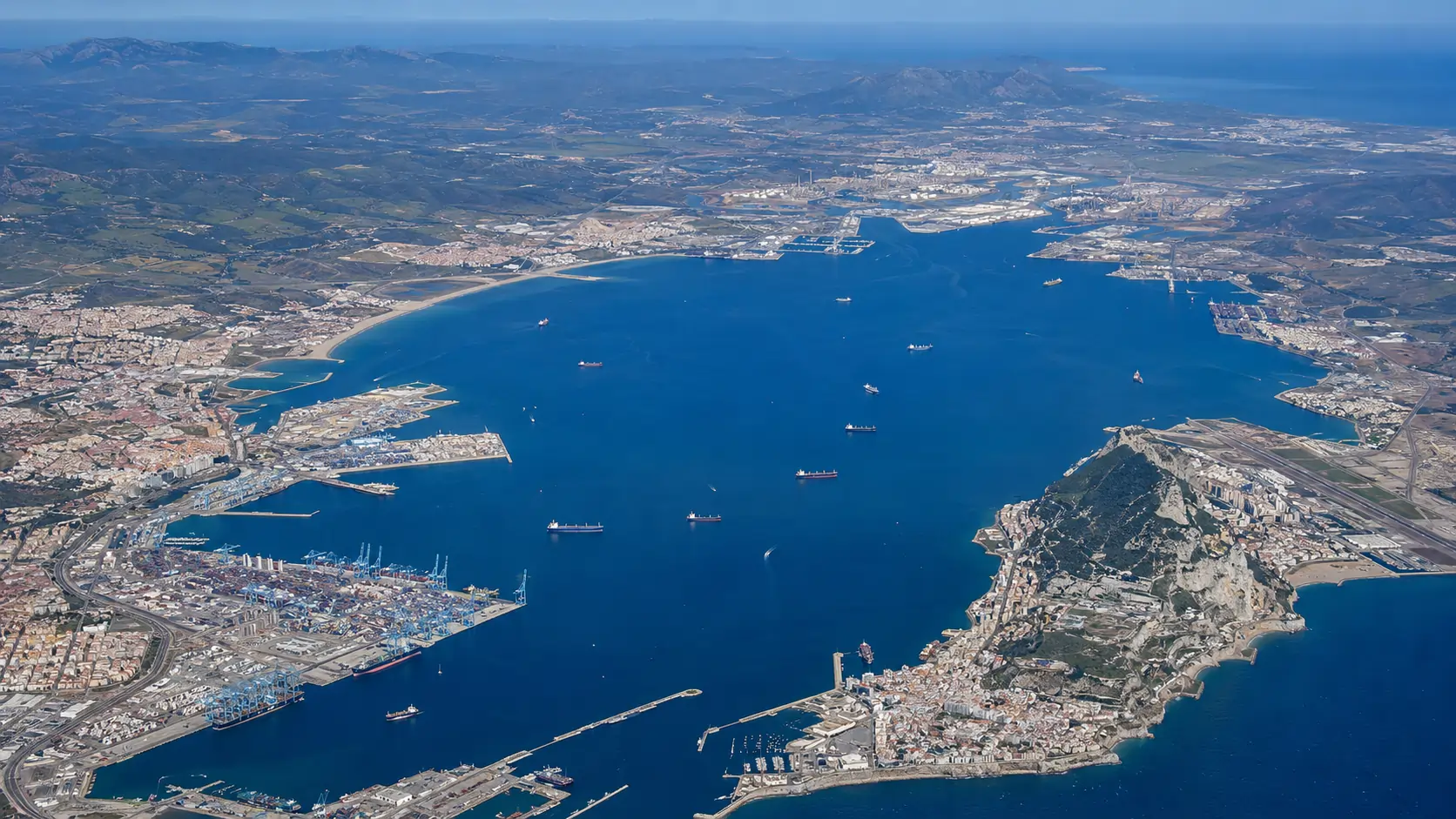 Aerial view along the Juan Carlos I container quay at the Port of Algeciras with ship-to-shore gantry cranes and a container vessel berthed alongside